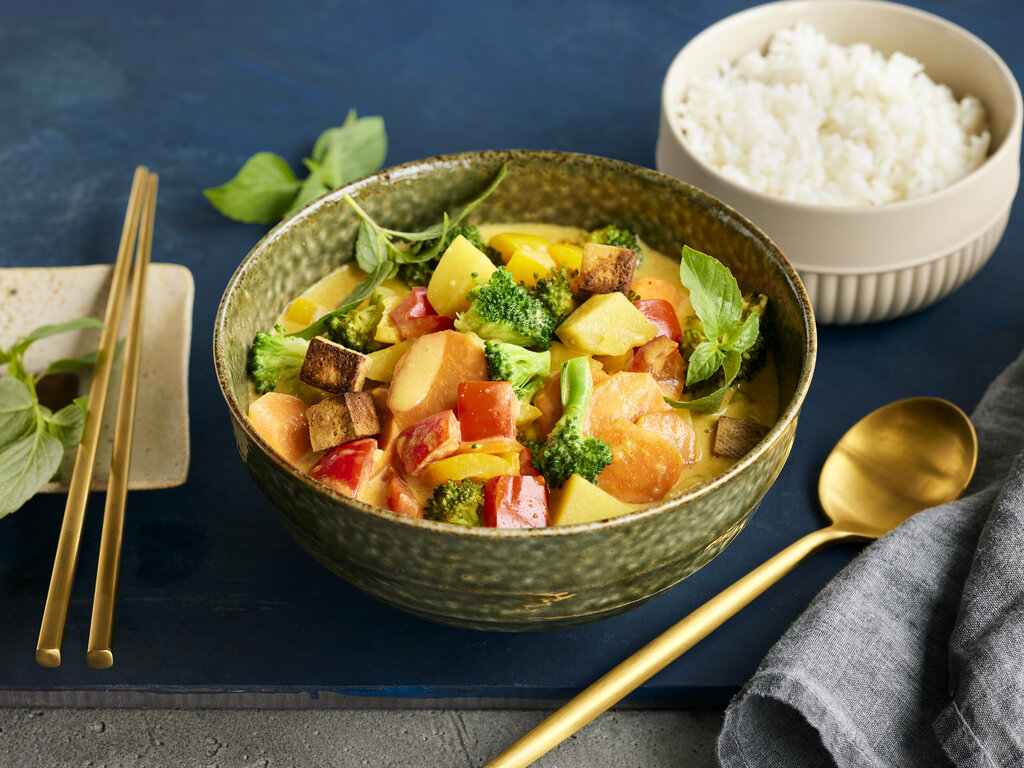 Veganes Thai-Curry - In einer grünen Schüssel wird das vegane Thai-Curry garniert mit Basilikum präsentiert